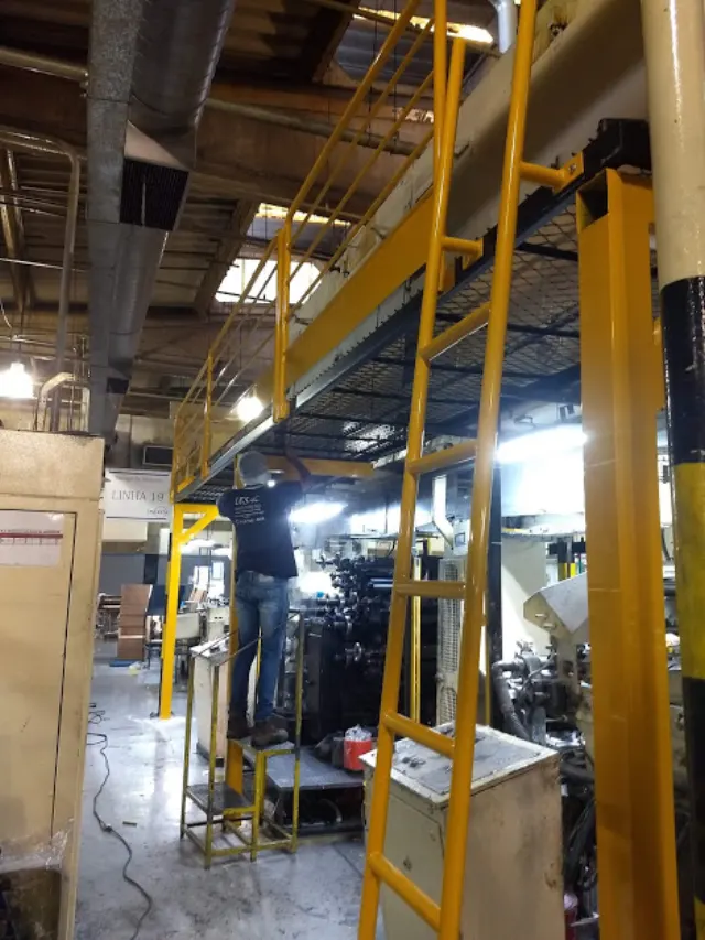 Plataforma e escada metálica amarela em ambiente industrial